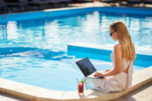 women sitting at pool doing remote work at a vacation rental